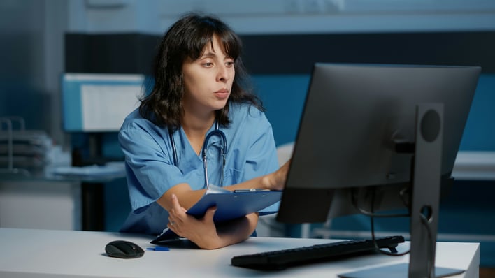 Healthcare professional reviewing systems on a computer